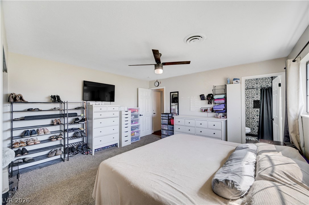 1331 Pinto Road Boulder City, NV 89005 - Photo 27 of 46 Well-lit primary bedroom featuring a ceiling fan, plush carpeting, and direct access to an attached bath.
