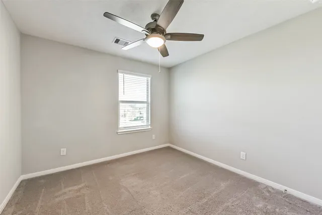 an empty room with a ceiling fan and a window