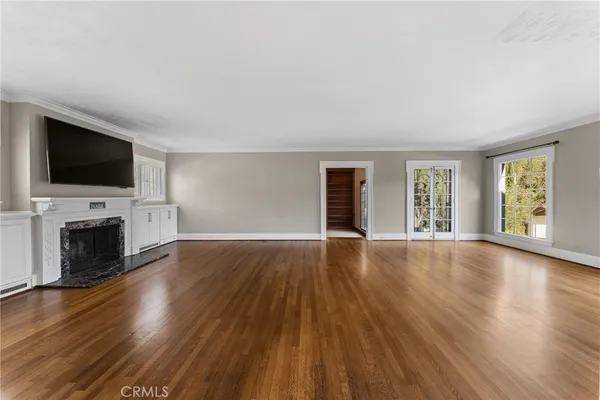 a view of an empty room with wooden floor and windows