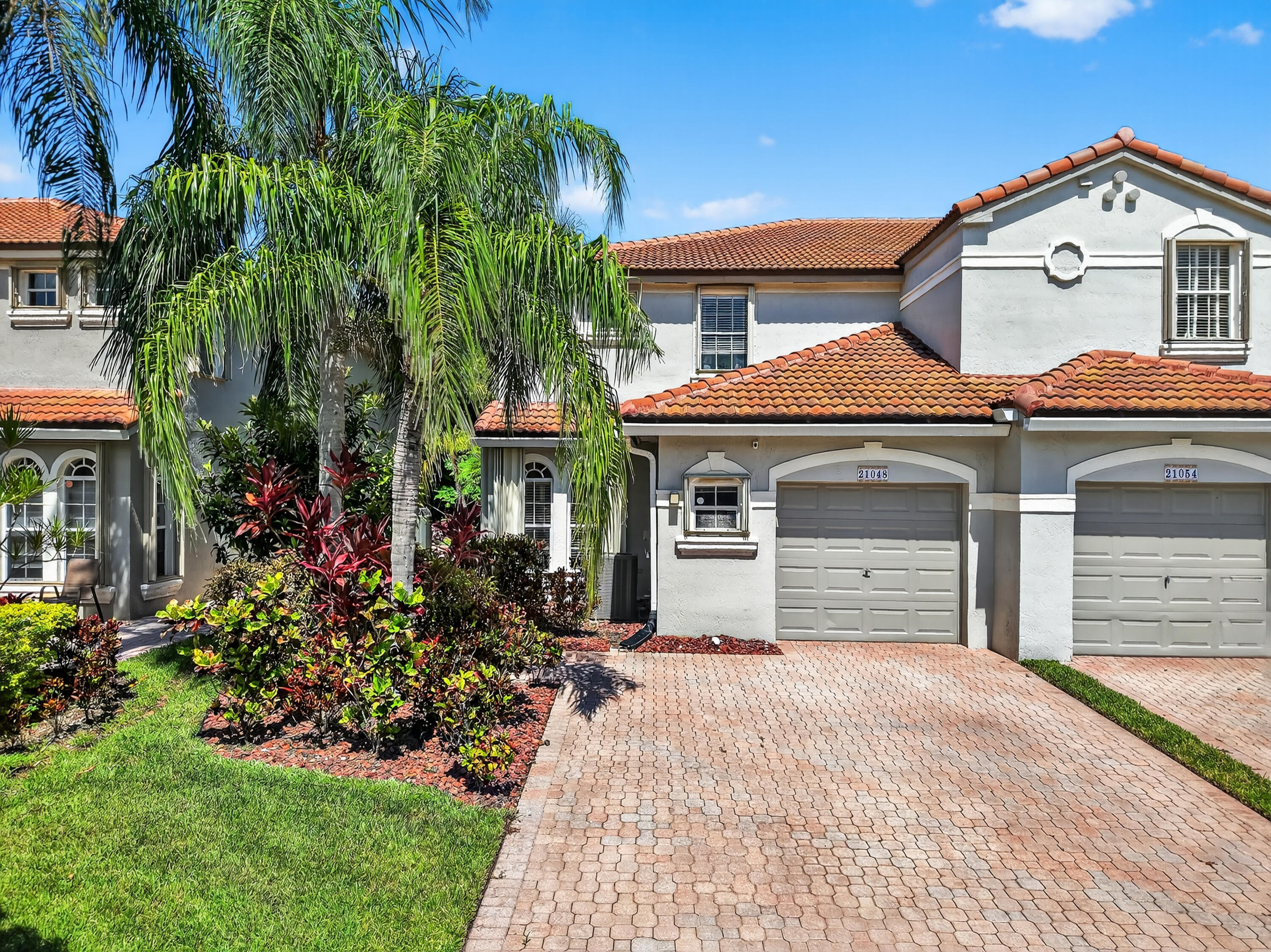 21048 Vía Eden Boca Raton, FL 33433 - Photo 26 of 53 a front view of a house with a yard and garage
