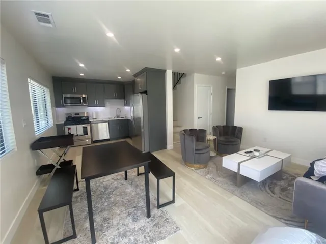 a living room with furniture a flat screen tv and kitchen view