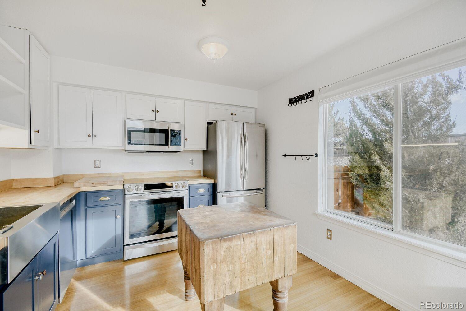 5174 Buckingham Road Boulder, CO 80301 - Photo 11 of 33 a kitchen with stainless steel appliances granite countertop a refrigerator a stove top oven a sink and white cabinets with wooden floor