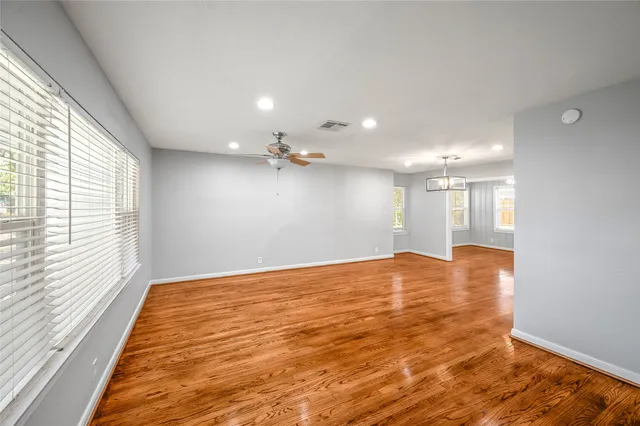 a view of an empty room with window and wooden floor