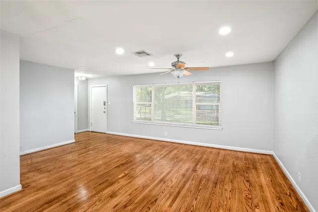 a view of an empty room with wooden floor and a window