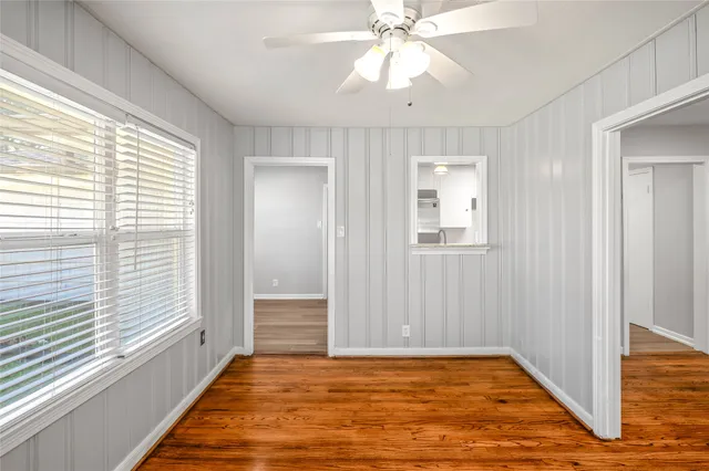 a view of an empty room with a window and wooden floor