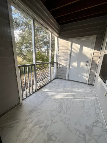 a view of a porch with wooden floor and door