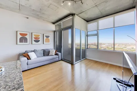 a living room with stainless steel appliances furniture a rug and a window