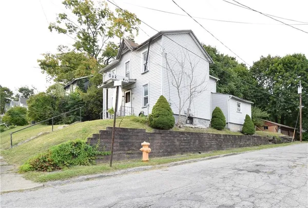 a view of a house with a yard and large tree