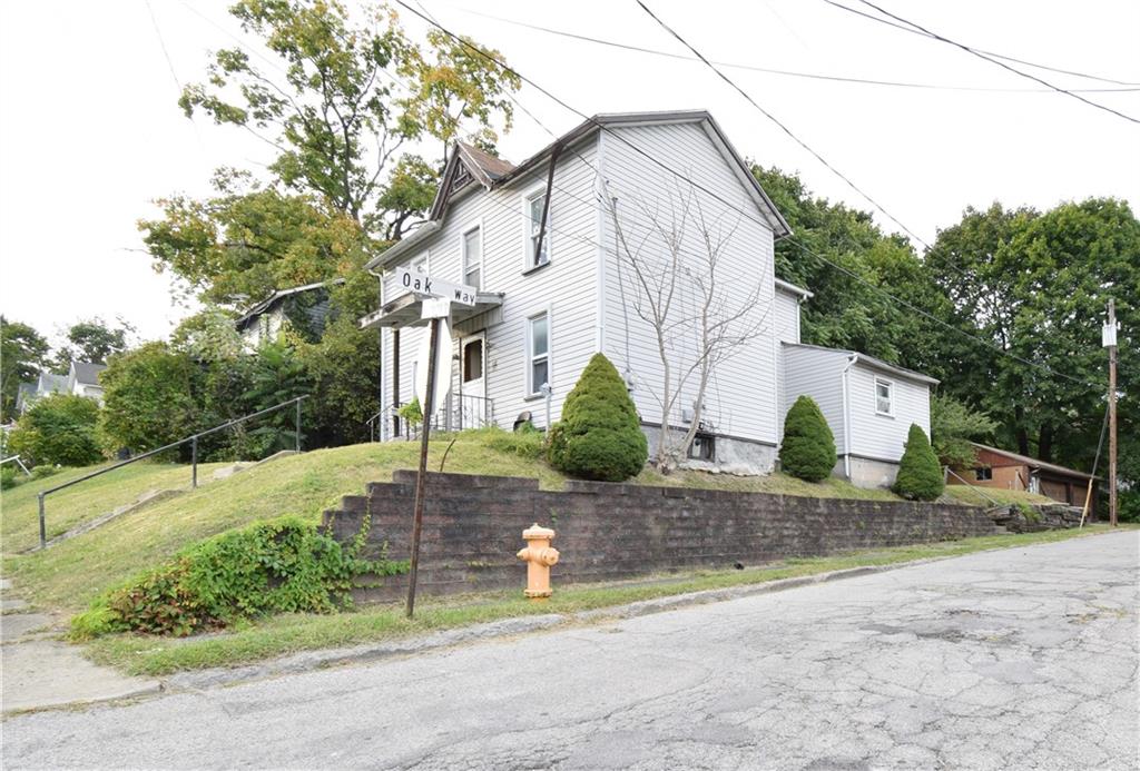 a view of a house with a yard and large tree