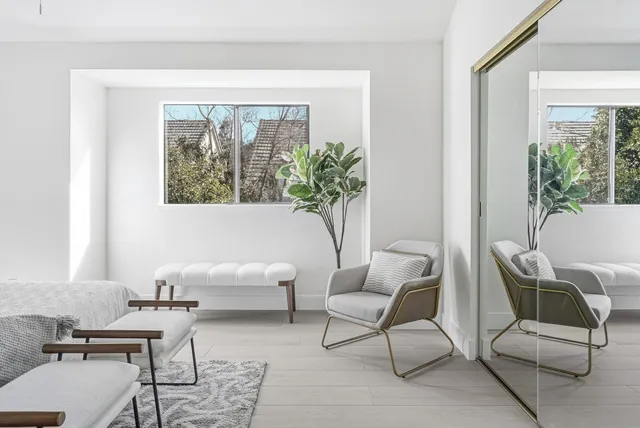 a bedroom with a bed mirror and couch