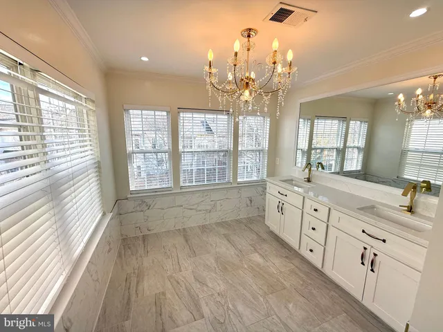 a spacious bathroom with double vanity a sink a large mirror and a large window