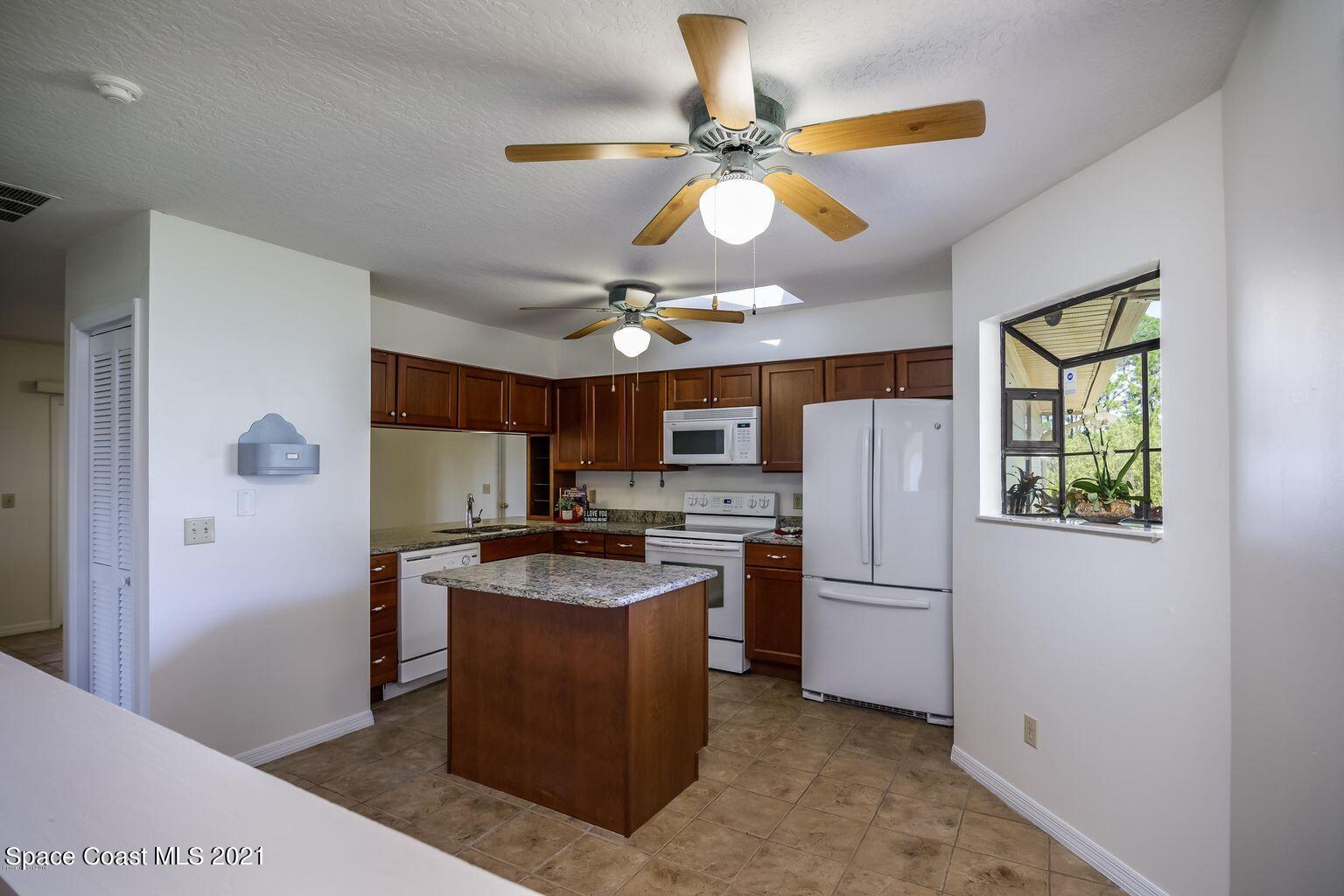 376 Trier Road Northwest Palm Bay, FL 32907 - Photo 4 of 16 a kitchen with stainless steel appliances granite countertop a refrigerator a stove a microwave oven a sink with a dining table and chairs