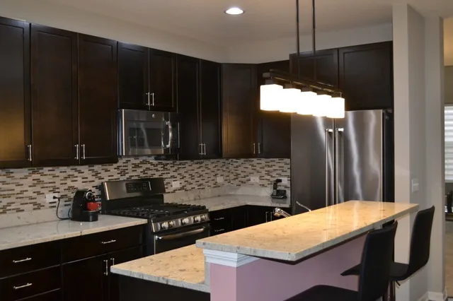 a kitchen with stainless steel appliances kitchen island granite countertop a stove refrigerator and cabinets