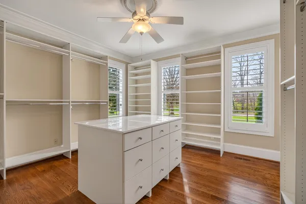 an empty room with windows and chandelier fan