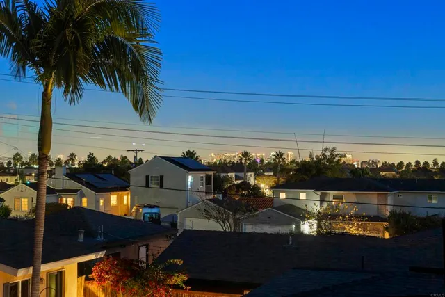 a view of a patio with couches table and chairs under an umbrella with a barbeque