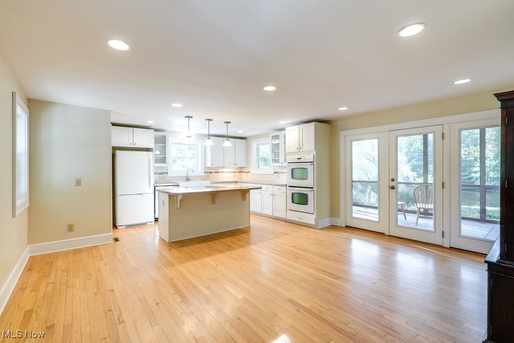 2980 Luli Road Mogadore, OH 44260 - Photo 19 of 50 Kitchen with pendant lighting, light wood-type flooring, a center island, white cabinetry, and white appliances