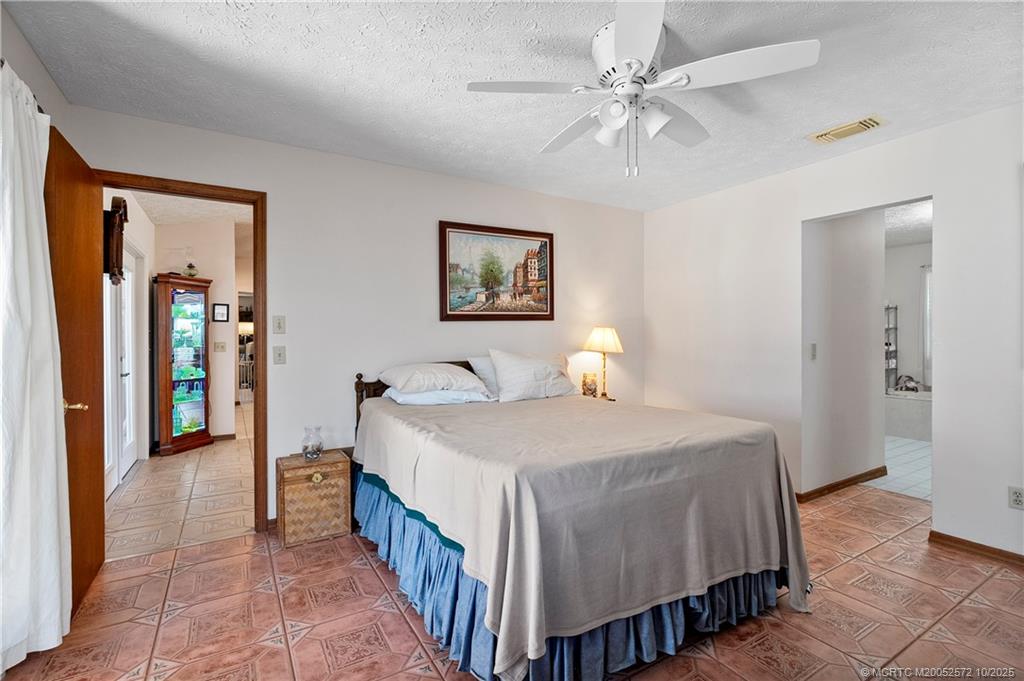 5145 Southeast Matousek Street Stuart, FL 34997 - Photo 16 of 52 a spacious bedroom with a bed and a chandelier