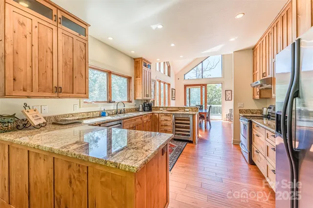 a kitchen with stainless steel appliances granite countertop a stove a sink dishwasher and a refrigerator with wooden floor