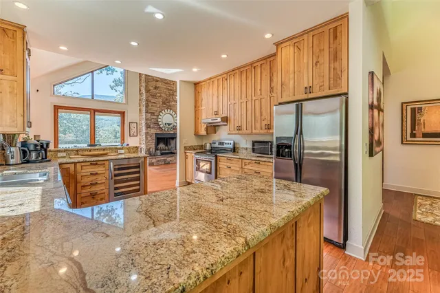 a kitchen with stainless steel appliances granite countertop a refrigerator a stove and a sink