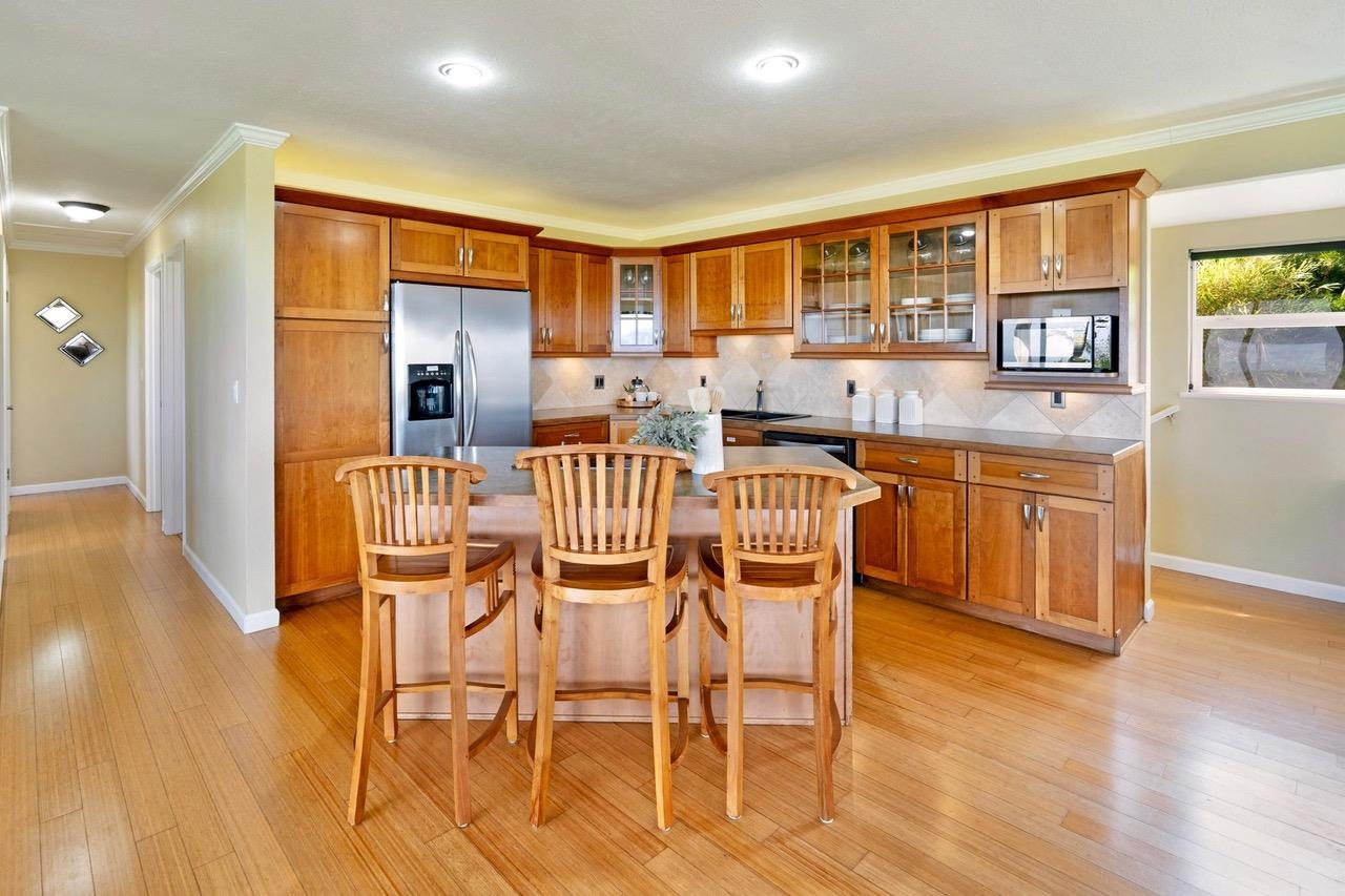 1115 Pookela Road Makawao, HI 96768 - Photo 16 of 37 a dining room with stainless steel appliances a dining table and chairs with wooden floor