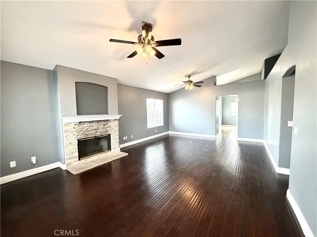 a view of a livingroom with wooden floor a fireplace and windows