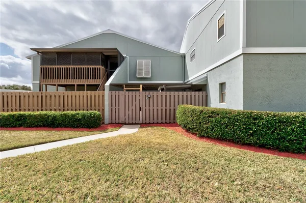 a view of a house with wooden fence next to a yard