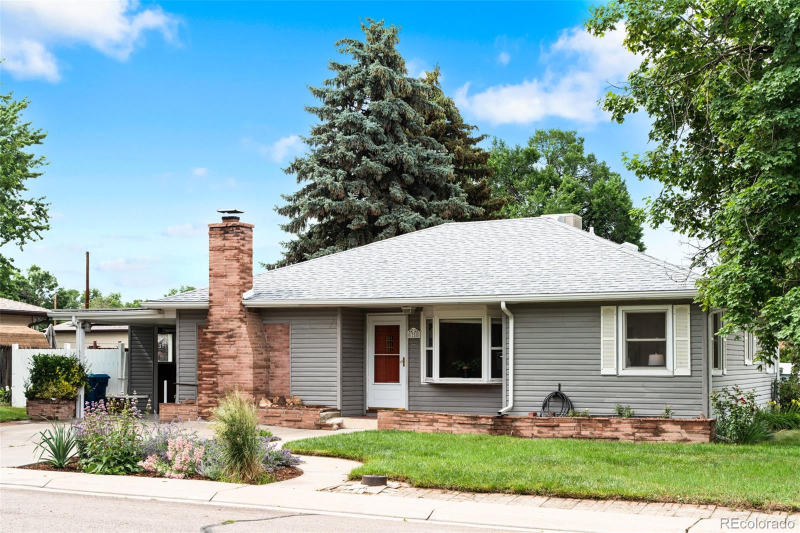 6755 West 45th Avenue Wheat Ridge, CO 80033 - Photo 3 of 27 a front view of a house with garden and trees