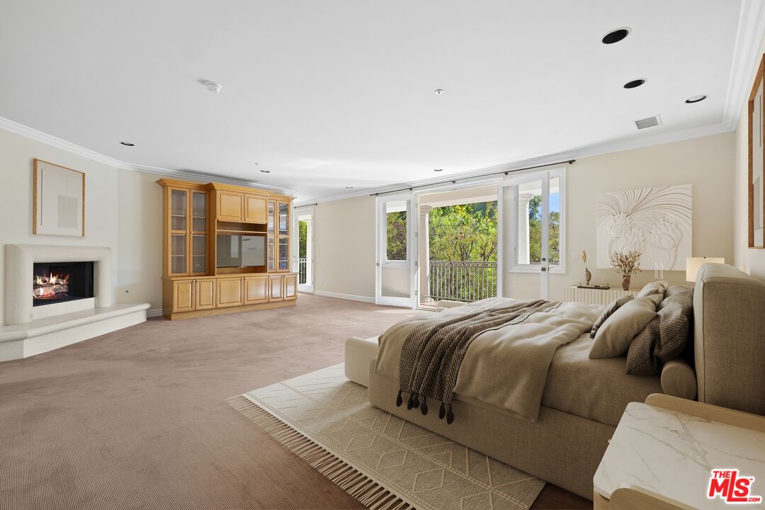 625 Foothill Road Beverly Hills, CA 90210 - Photo 13 of 22 a spacious bedroom with a large bed and a fireplace