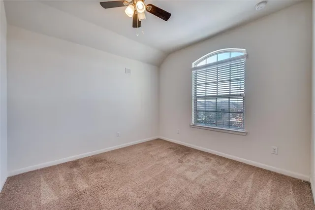 an empty room with a chandelier fan and windows