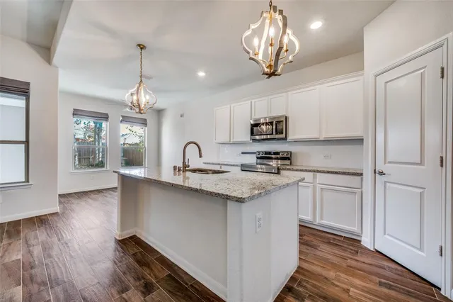 a kitchen with stainless steel appliances granite countertop a sink dishwasher a refrigerator cabinets and wooden floor