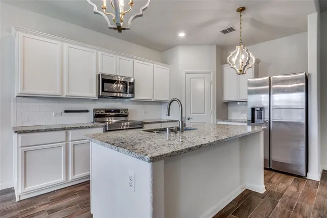 a kitchen with stainless steel appliances granite countertop a sink refrigerator and microwave