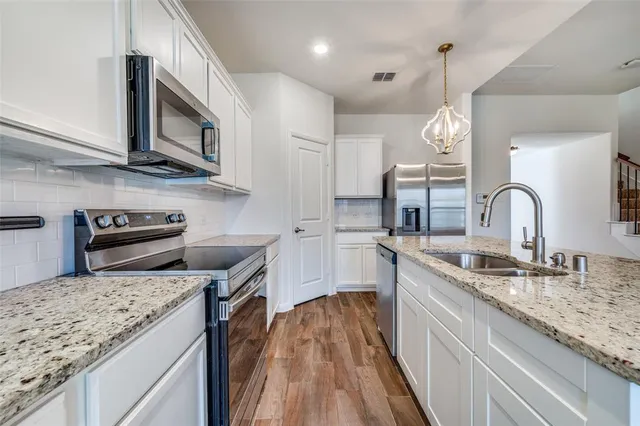 a kitchen with stainless steel appliances granite countertop a sink a stove and a wooden floors