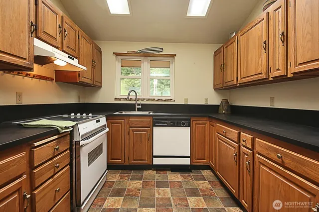 a kitchen with stainless steel appliances granite countertop a sink stove and cabinets