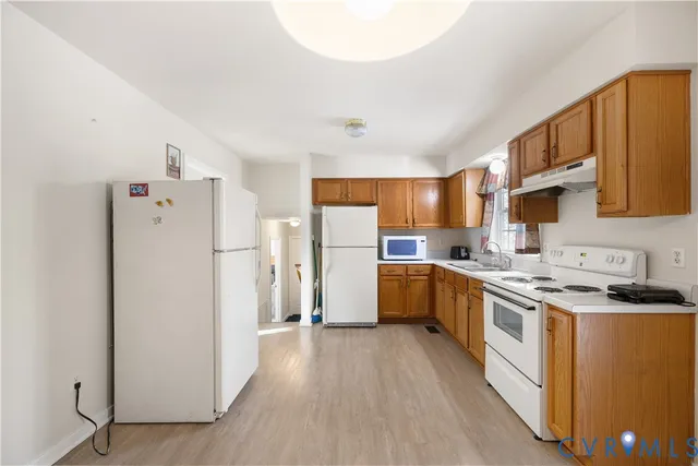 a kitchen with a refrigerator a stove top oven a sink and cabinets