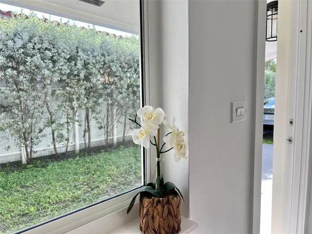 a vase of flowers sitting on a table with window