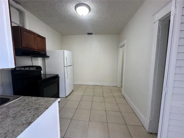 a kitchen with granite countertop a refrigerator and a stove top oven