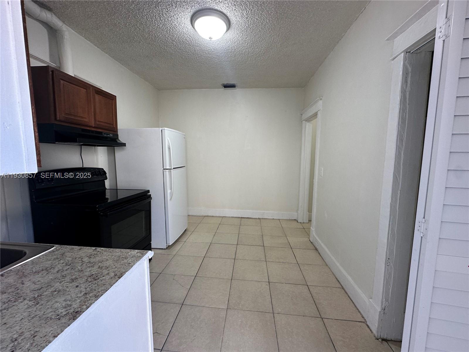 a kitchen with granite countertop a refrigerator and a stove top oven