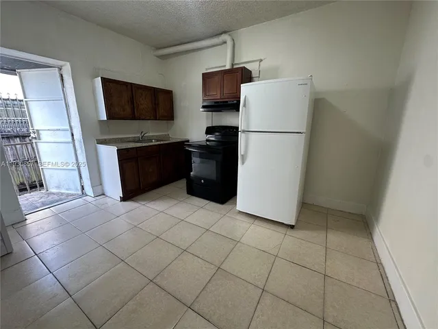 a kitchen with a refrigerator a stove top oven and a counter top space