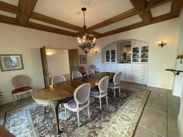 a view of a dining room with furniture a chandelier and large windows