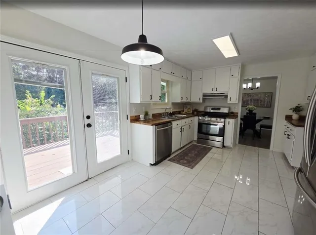 a kitchen with stainless steel appliances granite countertop a stove top oven a sink a counter space and cabinets