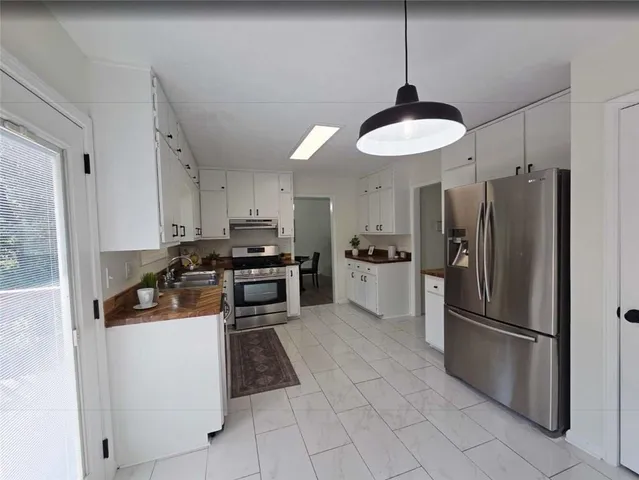 a kitchen with stainless steel appliances granite countertop a refrigerator a stove a sink and a refrigerator