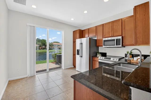 a kitchen with granite countertop a refrigerator and a stove top oven