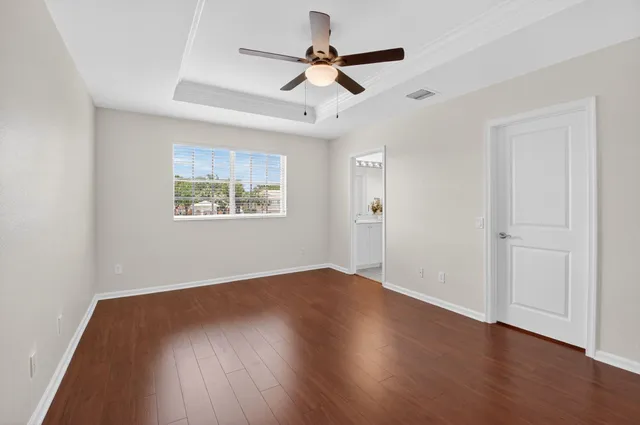 an empty room with wooden floor ceiling fan and windows