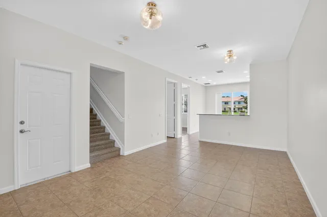 a view of an empty room with wooden floor and a ceiling fan