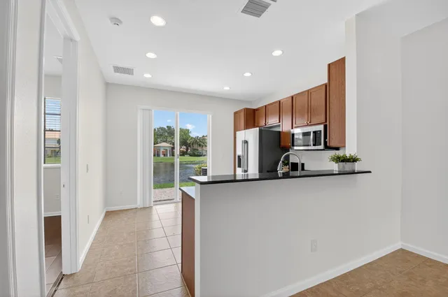 a view of a kitchen with stainless steel appliances wooden floor and a window