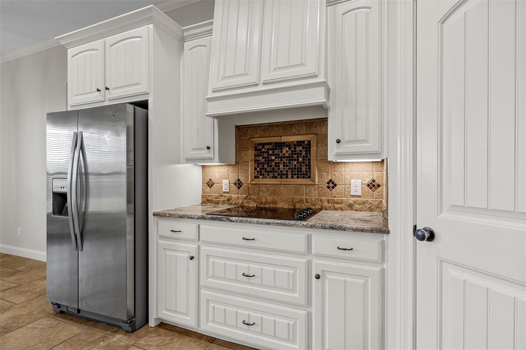144 Ellis Farm Road Hewitt, TX 76643 - Photo 12 of 36 Kitchen featuring white shaker-style cabinetry with dark hardware, a built-in cooktop, and a mosaic tile backsplash