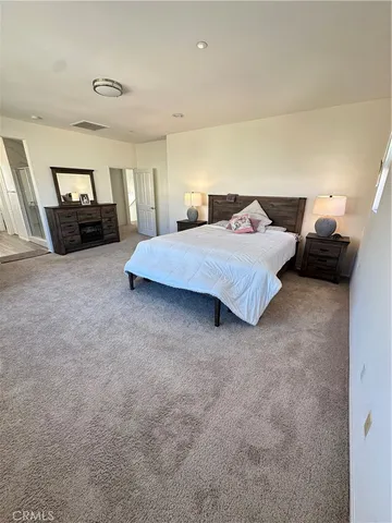 a spacious bedroom with a bed and wooden floor