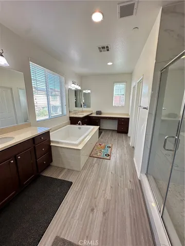 a large white kitchen with sink a refrigerator and wooden floor