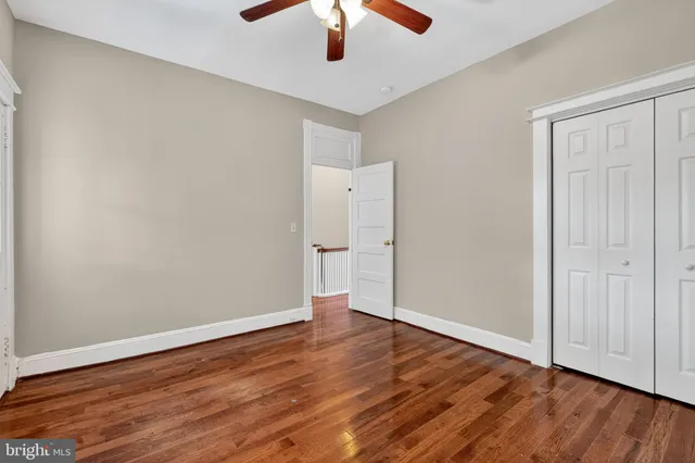 an empty room with wooden floor chandelier fan and windows