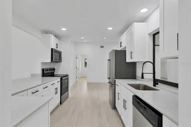 a kitchen with granite countertop a sink stove and refrigerator